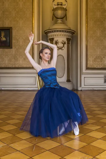 Balletttänzerin im blauen Kleid in einem historischen Saal